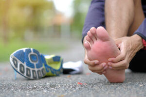 Woman holding foot with running shoe taken off after injury