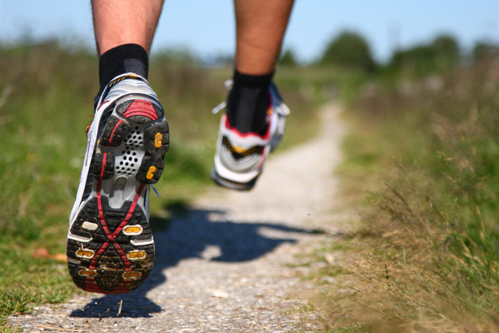 Trail running. Freeze action closeup of running shoes in action. Shallow depth of field, focus on left shoe.